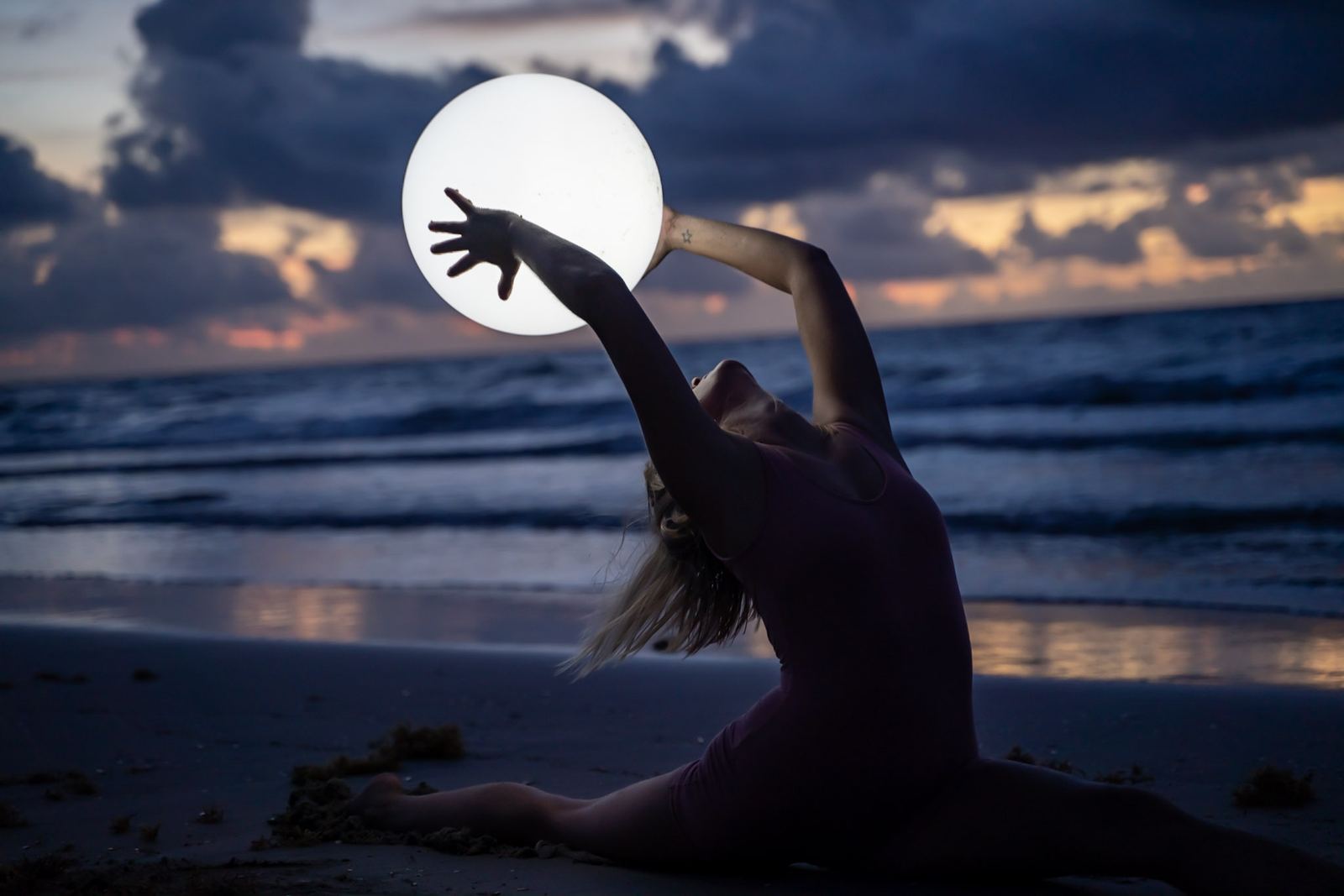 A yogi silhouetted against the full moon over the ocean